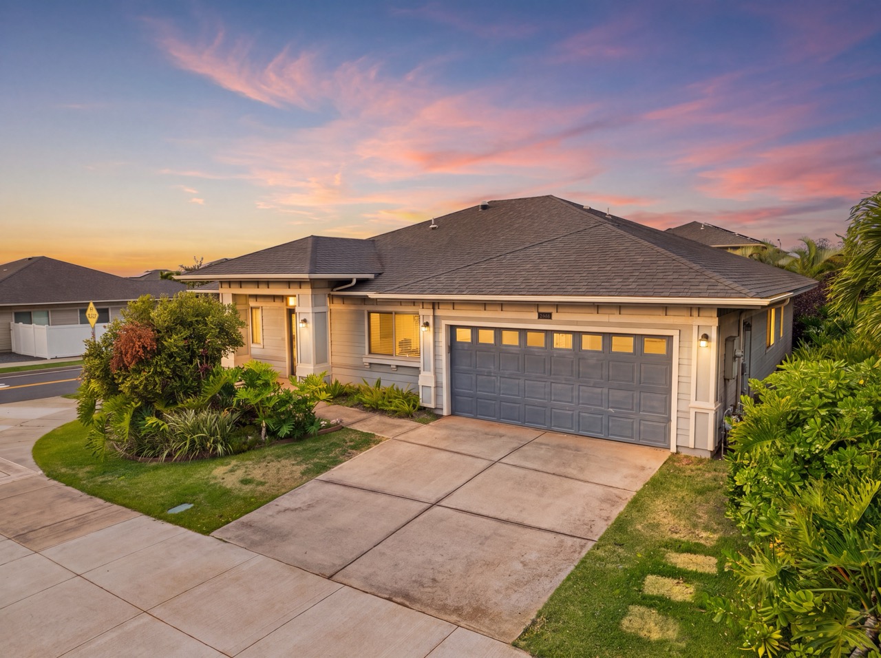 Twilight exterior view of 92-714 Welo St with two-car garage and landscaped front yard