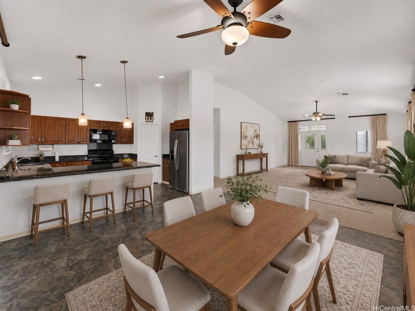 Open-concept kitchen, dining and living areas with vaulted ceilings and pendant lighting