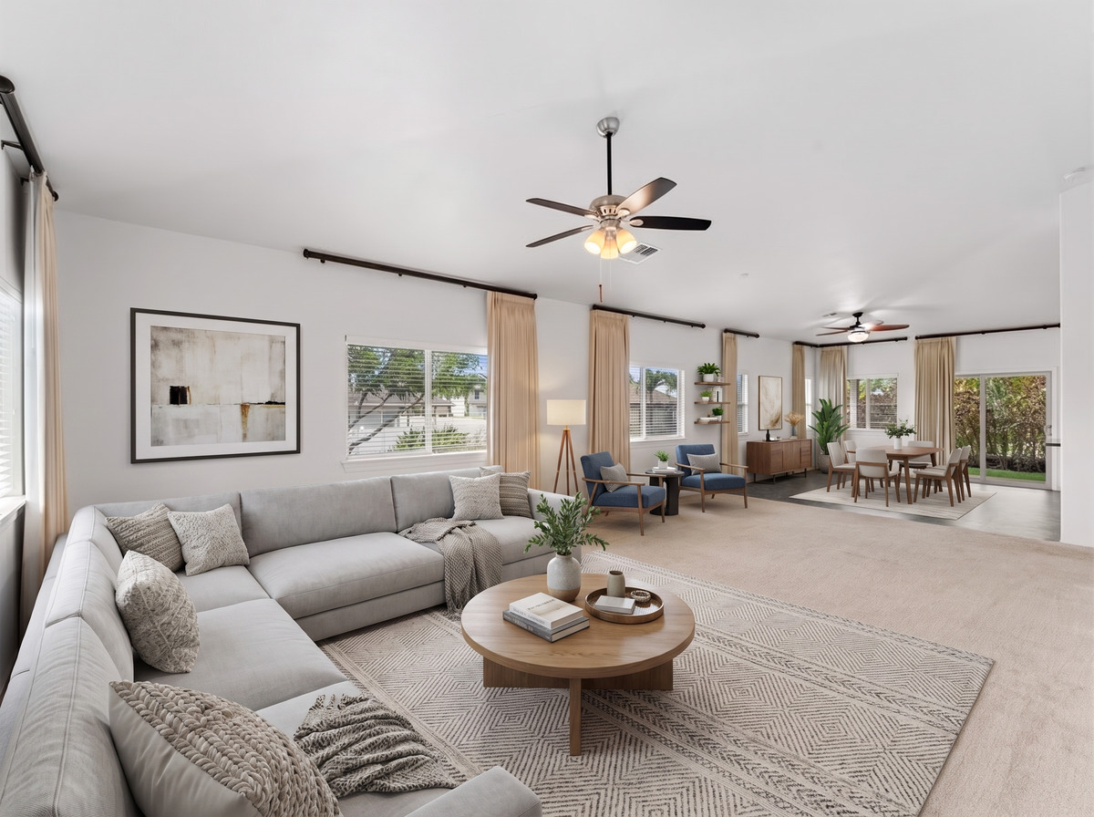 Spacious living room with vaulted ceiling, ceiling fan and open flow to the dining area
